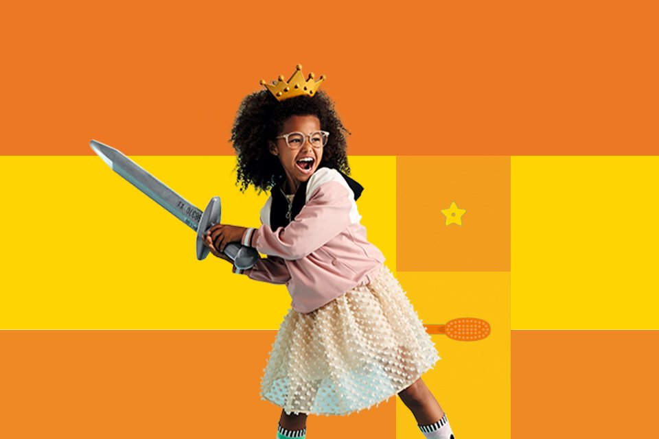 A girl wearing a crown pretending to be a princess against a yellow background.